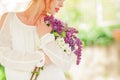 Beautiful woman with red hair holding white and violet lilac bloom in her hands, outdoor garden Royalty Free Stock Photo