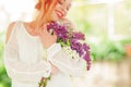 Beautiful woman with red hair holding white and violet lilac bloom in her hands, outdoor garden Royalty Free Stock Photo