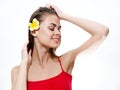 beautiful woman in a red t-shirt with a yellow flower in her hair touches her head with her hand Royalty Free Stock Photo