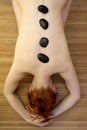 Beautiful woman relax black stones on back Royalty Free Stock Photo