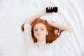 Beautiful woman relaxing on bed and holding smartphone Royalty Free Stock Photo