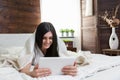 Beautiful woman relaxing on the bed and using her tablet Royalty Free Stock Photo