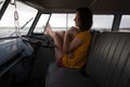 Beautiful woman relaxing in camper van with his foot outside against beach in background Royalty Free Stock Photo