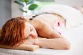 Beautiful woman relaxing in spa salon with hot stones on body. Royalty Free Stock Photo