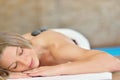 Beautiful woman relaxing in spa salon with hot stones on body. Beauty treatment therapy Royalty Free Stock Photo