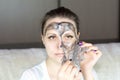 Beautiful woman removes cleansing black mask from face Royalty Free Stock Photo