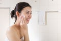 Beautiful woman removing makeup from her face in bathroom.