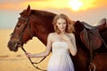 Beautiful woman riding a horse at sunset on the beach. Young girl with a horse in the rays of the sun by the sea. Royalty Free Stock Photo