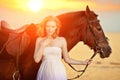 Beautiful woman riding a horse at sunset on the beach. Young girl with a horse in the rays of the sun by the sea. Royalty Free Stock Photo