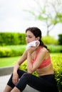 Beautiful woman runner has used a white towel wipe her face after running in the garden