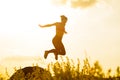 Beautiful Woman Runner Jumping from the Rock on the Mountain Trail at Hot Summer Sunset. Sport and Active Lifestyle. Royalty Free Stock Photo