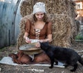 Beautiful woman in a rustic dress sits on a hay and sifts the grain Royalty Free Stock Photo