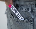 A beautiful woman`s hand with a bright manicure takes a paper with the inscription Possibility from the pocket of her jeans. Phot Royalty Free Stock Photo