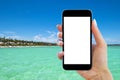 Beautiful woman`s hand using smart phone at tropicL beach. Near ocean. Smartphone isolated white screen. Blank empty screen. Empty Royalty Free Stock Photo