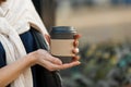 Beautiful woman`s hands with cup of coffeen in craft paper in the street Royalty Free Stock Photo