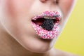 Beautiful woman's mouth full of colorful sugar pearls