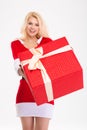 Beautiful woman in santa claus dress giving you red gift Royalty Free Stock Photo