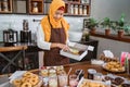 Beautiful woman in scarf preparing donuts packing into donut boxes