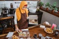 Beautiful woman in scarf preparing donuts packing into donut boxes