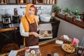 Beautiful woman in scarf smiling happily in the kitchen preparing donuts packing