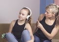 Beautiful woman is scolding her teenage daughter, girl is listening to music in headphones and ignoring her mom