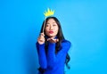 Beautiful woman send air kiss holding paper crown on stick isolated on blue background