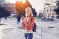 Beautiful woman is sending a text message using an app on her smartphone while walking in the street on a sunset background Royalty Free Stock Photo