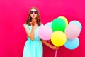 Beautiful woman is sends an air kiss holds an air colorful balloons on pink background Royalty Free Stock Photo