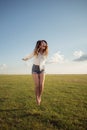 Beautiful woman with legs and denim shorts jumping on grass, shoe less Royalty Free Stock Photo