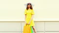 Beautiful woman with shopping bags wearing yellow dress and summer straw hat in the city Royalty Free Stock Photo