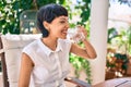 Beautiful woman with short hair sitting at the terrace on a sunny day drinking a fresh glass of water Royalty Free Stock Photo