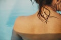 Beautiful woman shoulder with water drops close up, relaxing in pool. Back view of brunette girl with wet skin with goosebumps. Royalty Free Stock Photo