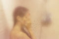 Beautiful woman in the shower behind glass with drops. Royalty Free Stock Photo