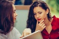 Beautiful woman shows her friend information on tablet screen Royalty Free Stock Photo