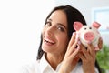 Beautiful woman shows piggy bank and smiles