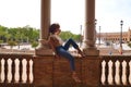 Beautiful woman is sightseeing in seville, the woman is sitting between two columns in the biggest and most famous square in