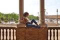 Beautiful woman is sightseeing in seville, the woman is sitting between two columns in the biggest and most famous square in