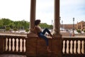 Beautiful woman is sightseeing in seville, the woman is sitting between two columns in the biggest and most famous square in