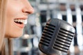 Beautiful woman singing on the stage next to the microphone.