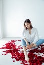 a beautiful woman sit in the flowers of the petals of red roses Royalty Free Stock Photo