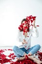 a beautiful woman sit in the flowers of the petals of red roses Royalty Free Stock Photo