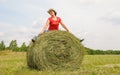 Beautiful woman sits on a hay in a field Royalty Free Stock Photo