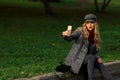 Beautiful woman sits on the road and taking selfie with smartphone in autumn park. Royalty Free Stock Photo