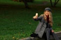 Beautiful woman sits on the road and taking selfie with smartphone in autumn park. Royalty Free Stock Photo