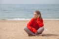 Beautiful blonde woman sits on the sand on an empty beach by the sea Royalty Free Stock Photo