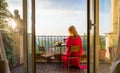 Woman sitting on balcony and overlooking city in morning at sunrise Royalty Free Stock Photo