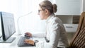 Beautiful young woman sitting behind desk and using computer Royalty Free Stock Photo