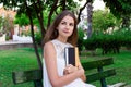 Beautiful woman is sitting on the bench and thinking about something holding a book in the park Royalty Free Stock Photo