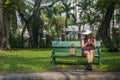 Beautiful woman sitting on a bench and watching messages on a smartphone in the garden Royalty Free Stock Photo
