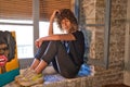 Beautiful woman sitting on the edge of a large window in her studio while making different expressions of joy and depression. Royalty Free Stock Photo